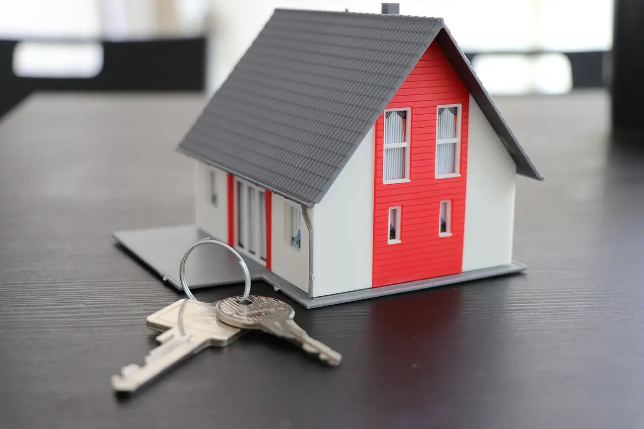 Immobilien Kauf - Verkauf - Kleines Haus wo ein Schlüssel davor liegt.